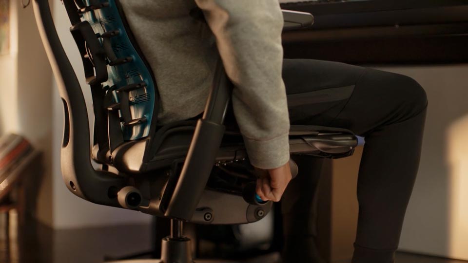 A close-up image of the side of the Embody Gaming Chair with a person adjusting seat height mechanism.
