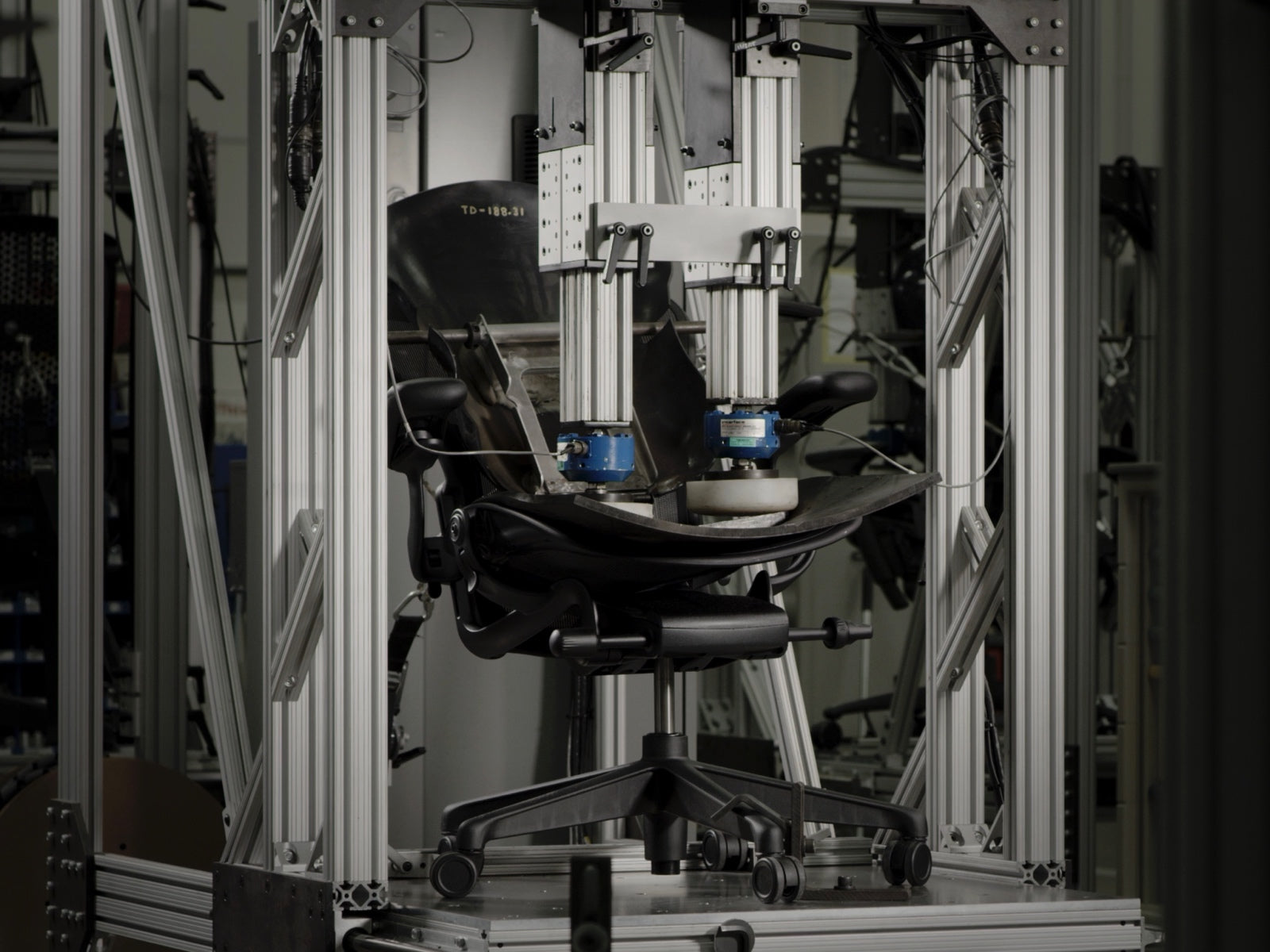 An Aeron Gaming Chair, shown from the side, in a testing machine at the Herman Miller manufacturing site.